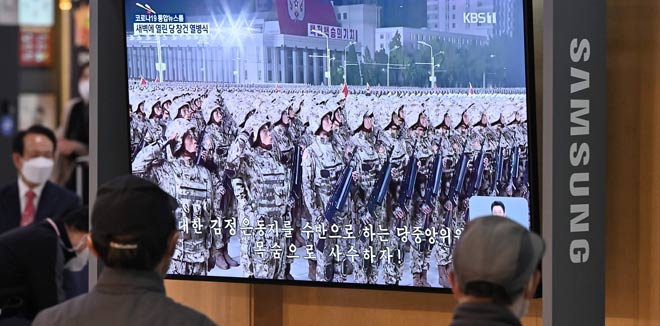 North Koreans rally wearing masks after military parade