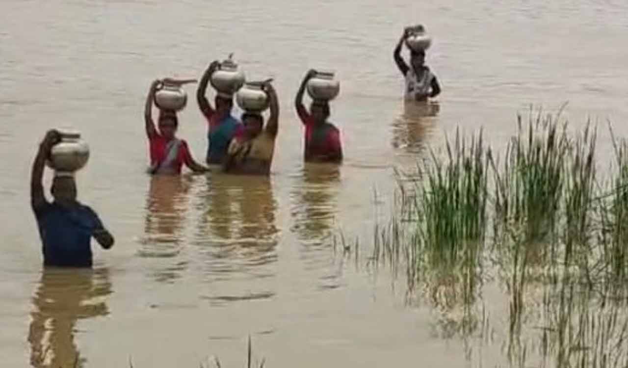Women wade through flooded river to fetch drinking water in Asifabad