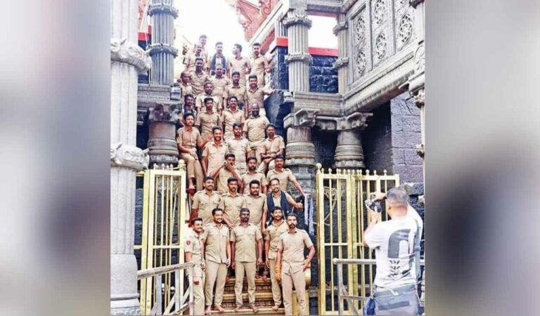 The picture was taken on Saturday which shows about 28 policemen in uniform with their backs to the sanctum sanctorum, which according to customs and traditions is a gross violation according to the devotees and believers of Lord Ayyappa, the temple deity.