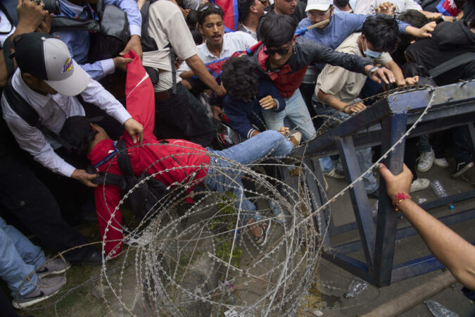 A protester falls down during clashes with riot police outside the parliament building in Kathmandu, Nepal.