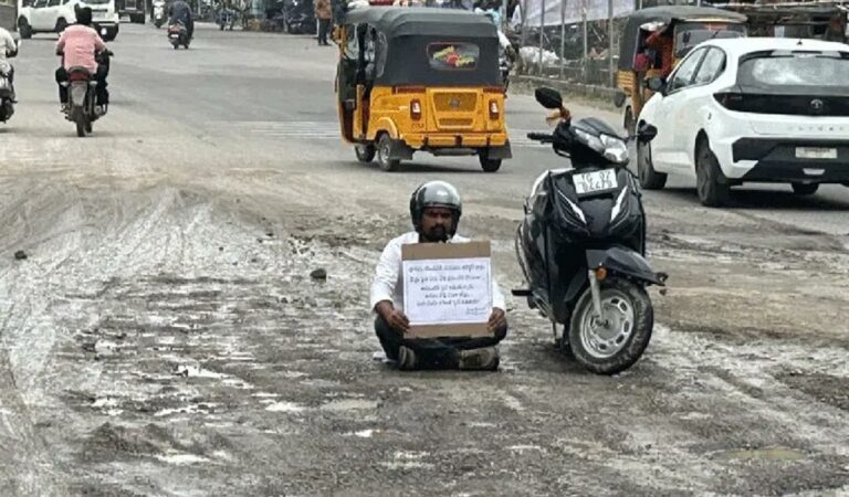 Social worker Shyam staging protest by sitting on damaged road in Karimnagar on Wednesday.