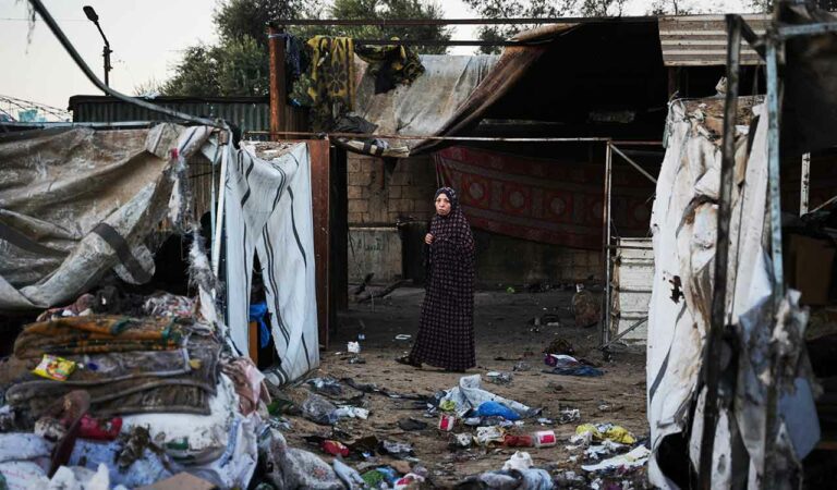 Displaced Palestinians inspect the damage after an Israeli army strike on their tent camp in Deir al-Balah, Gaza Strip