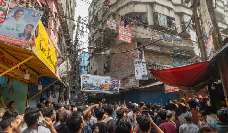 People gather outside a narrow lane in old city area where a roof and wall collapsed, after an earthquake in Dhaka, Bangladesh