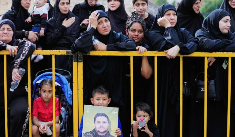 Mourners gather behind barriers attend the funeral procession of five Hezbollah fighters killed in Israeli strikes in recent days, in the southern town of Nabatieh, Lebanon.