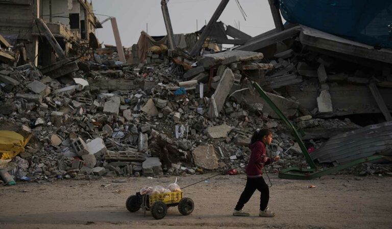 A girl carries bread as she walks past destruction left by Israeli air and ground operations in Gaza City